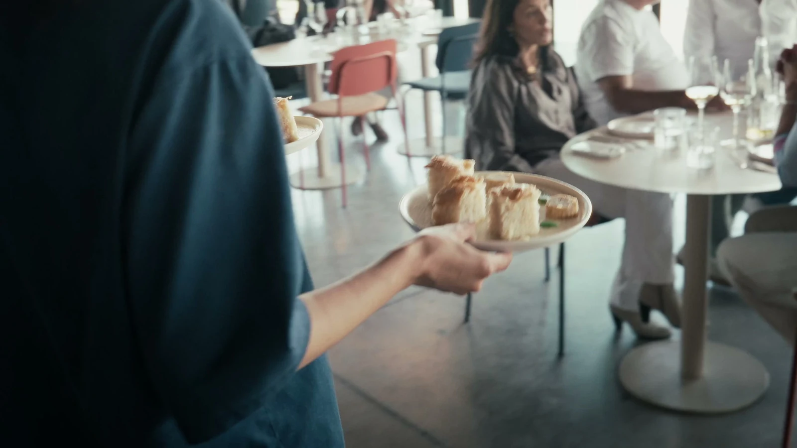 Someone from Püra carrying a tray of focaccia between the tables