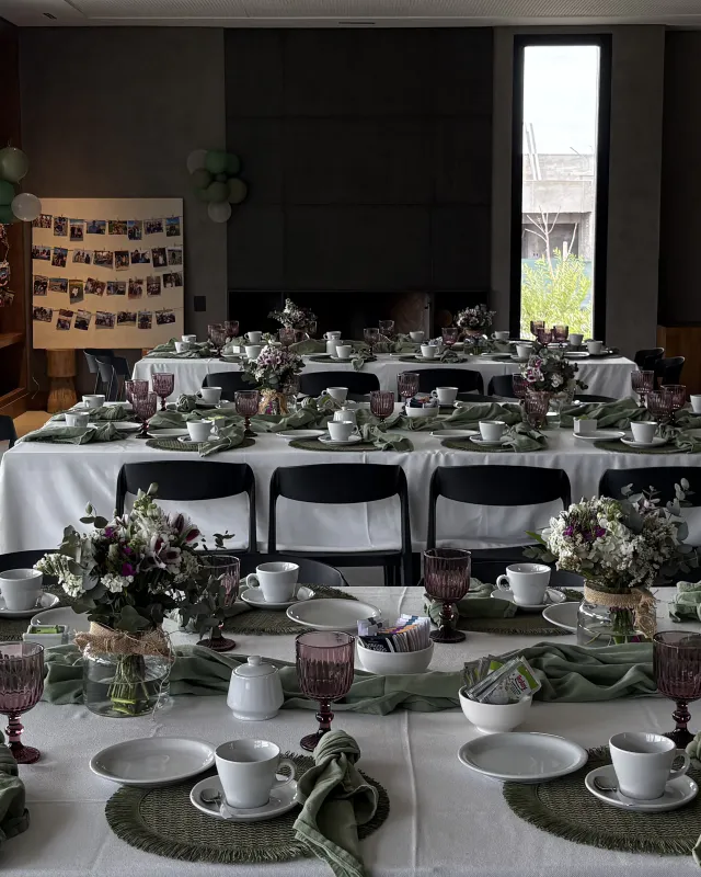 Long tables with white tablecloths, glasses, flowers and green napkins, set for an 80th birthday party