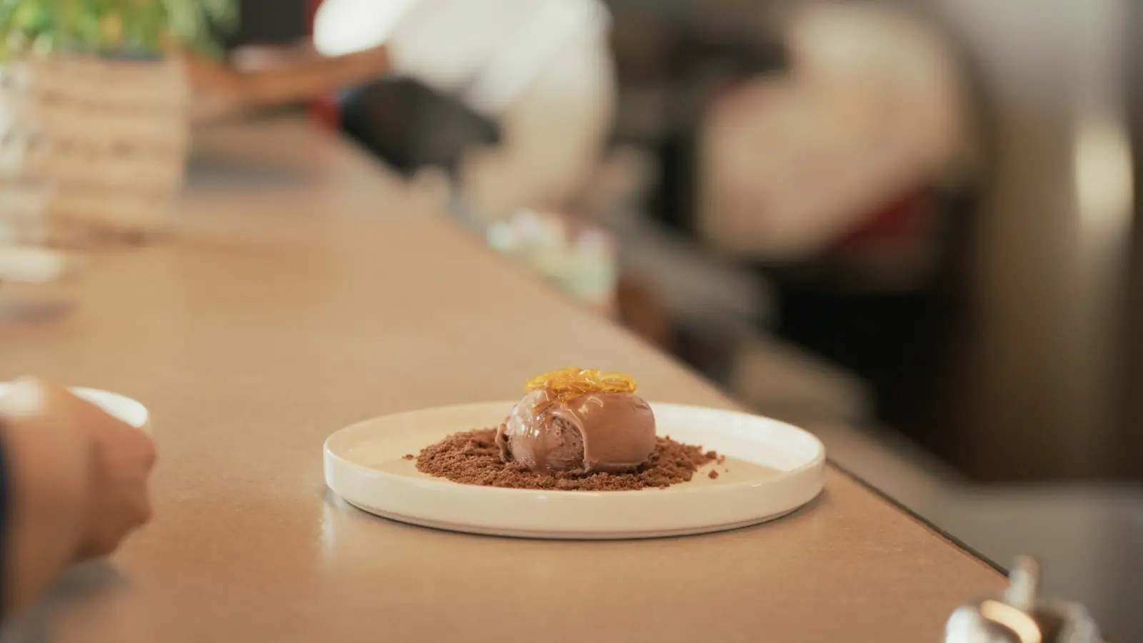 Cacao and earth dessert: chocolate ice cream on cocoa crumble with caramel threads, on the bar